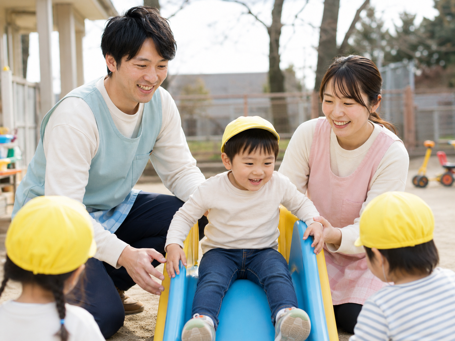 園庭で滑り台あそびをサポートする保育士